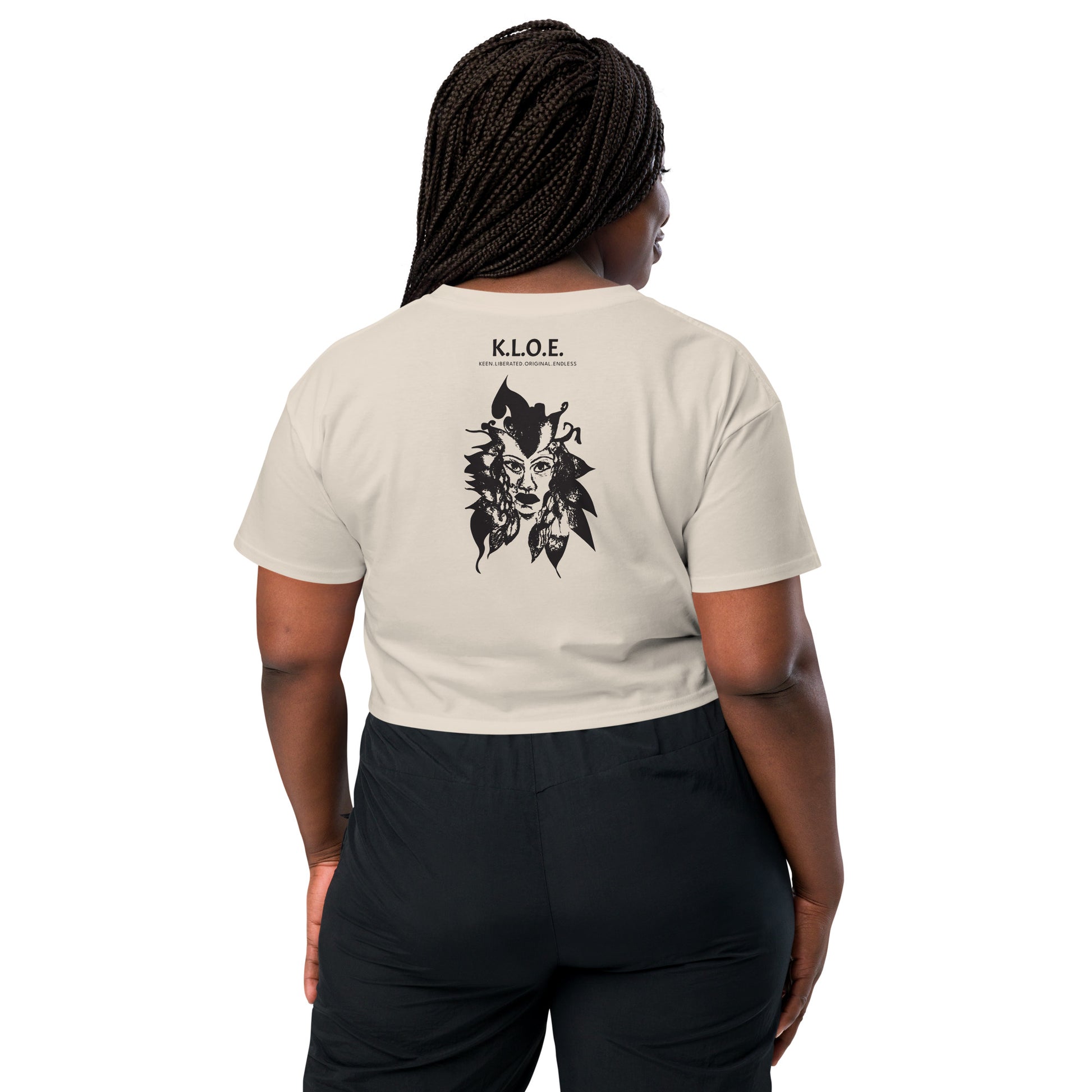 Back view of a bone K.L.O.E. crop t-shirt showcasing a culturally inspired, hand-drawn black design featuring a bold, expressive face intertwined with flowing, abstract patterns, and K.L.O.E. logo, embodying artistic self-expression and modern bohemian style fashion, on a model.