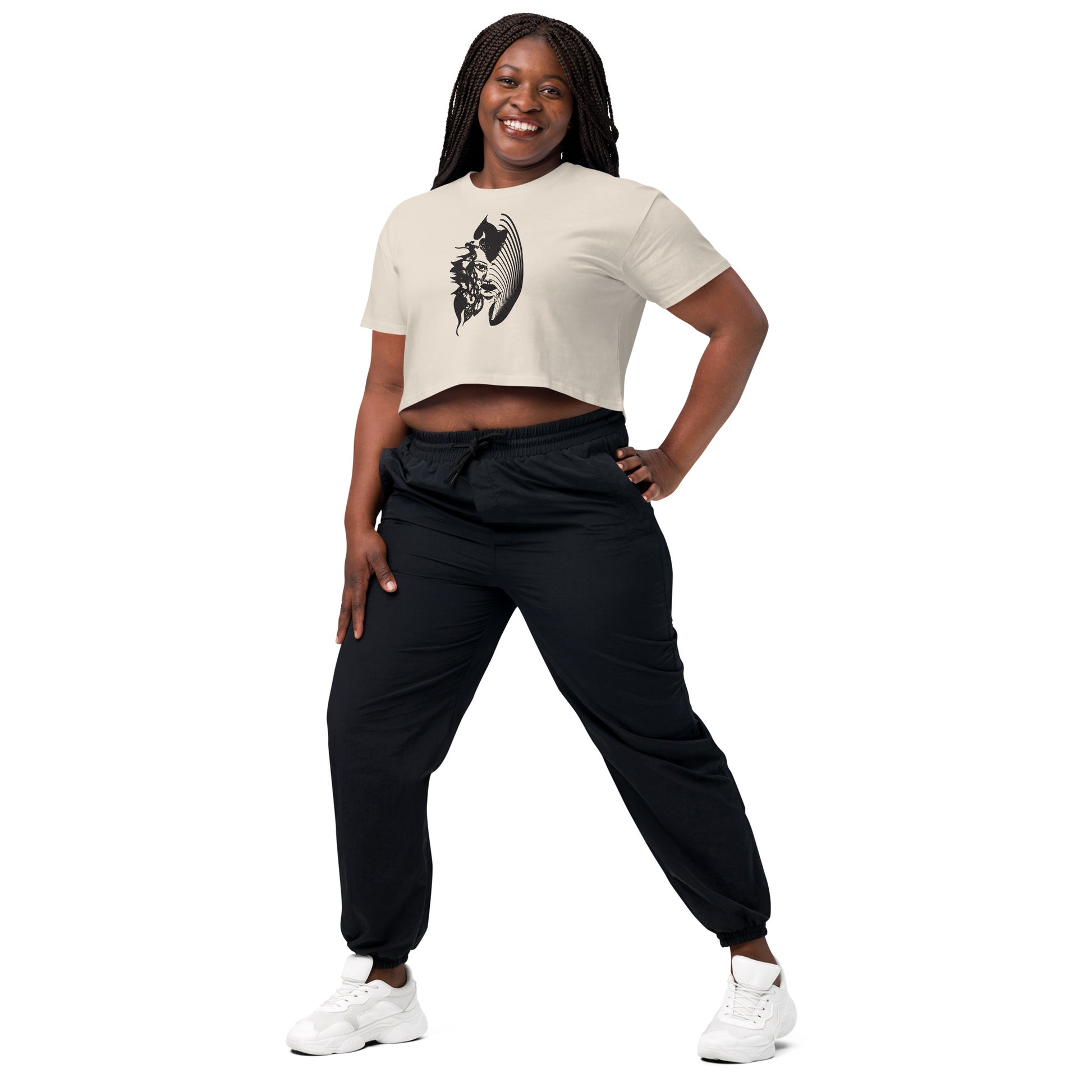 A model wearing a bone K.L.O.E. crop t-shirt featuring a culturally inspired, hand-drawn black graphic of a bold, expressive face surrounded by intricate details, celebrating individuality and artistic self-expression in modern bohemian style fashion.