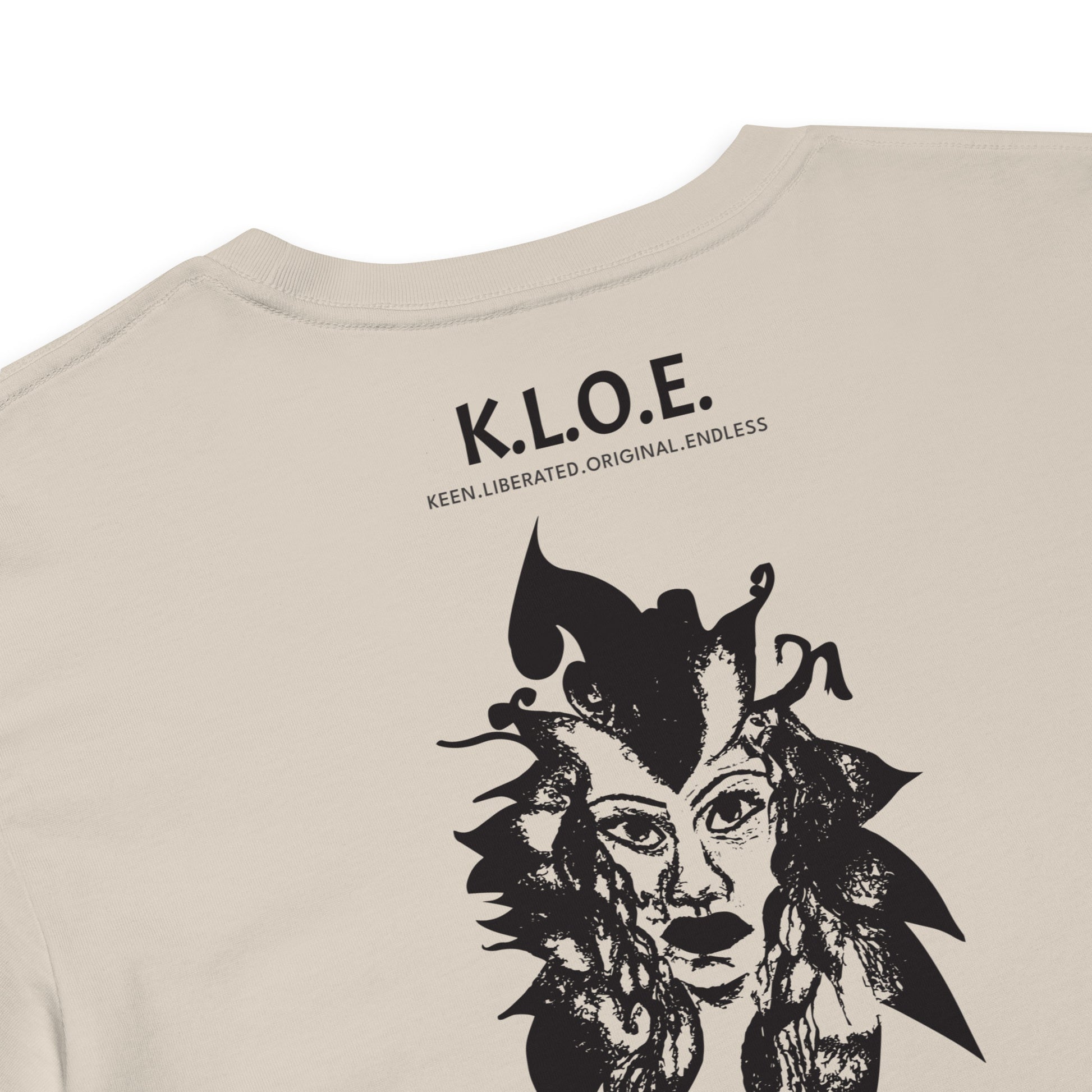 Detail view of a back side of a bone K.L.O.E. crop t-shirt showcasing a culturally inspired, hand-drawn black design featuring a bold, expressive face intertwined with flowing, abstract patterns, and K.L.O.E. logo, embodying artistic self-expression and modern bohemian style fashion.
