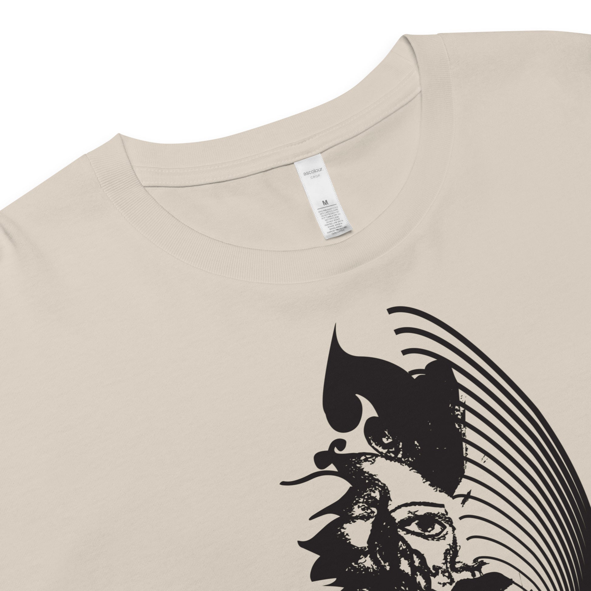 Detail view of a bone K.L.O.E. crop t-shirt featuring a culturally inspired, hand-drawn black graphic of a bold, expressive face surrounded by intricate details, celebrating individuality and artistic self-expression in modern bohemian style fashion.