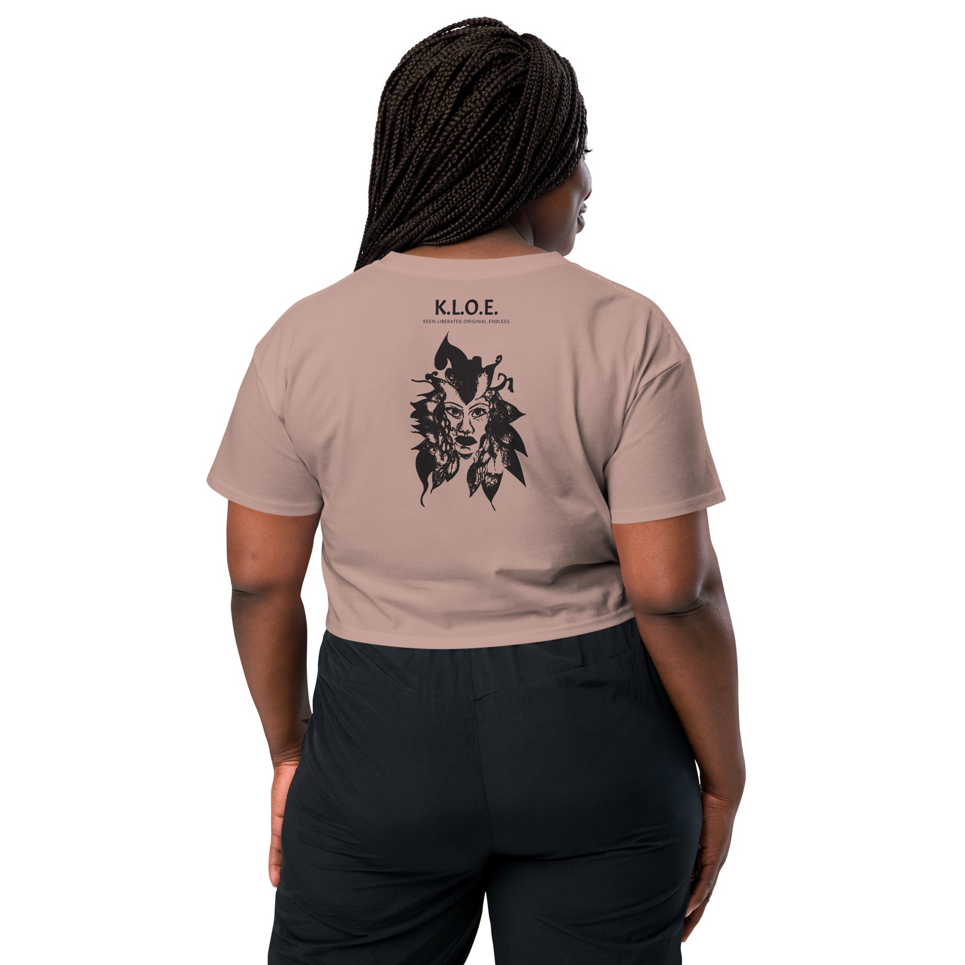 Back view of a hazy pink K.L.O.E. crop t-shirt showcasing a culturally inspired, hand-drawn black design featuring a bold, expressive face intertwined with flowing, abstract patterns, and K.L.O.E. logo, embodying artistic self-expression and modern bohemian style fashion, on a model.