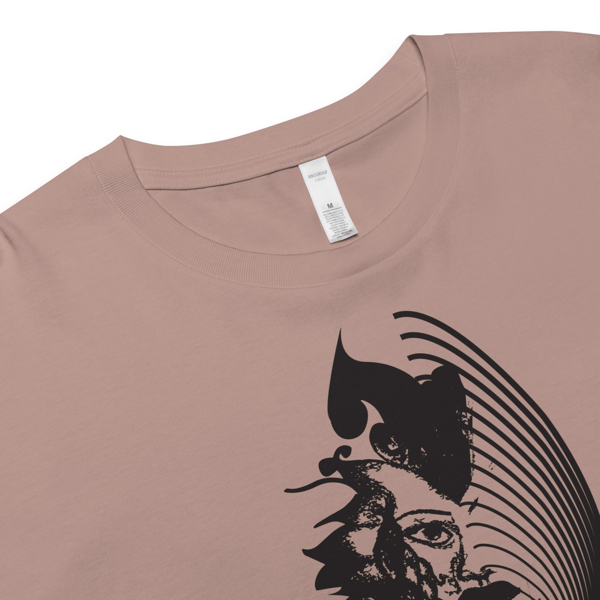 Detail view of a hazy pink K.L.O.E. crop t-shirt featuring a culturally inspired, hand-drawn black graphic of a bold, expressive face surrounded by intricate details, celebrating individuality and artistic self-expression in modern bohemian style fashion.