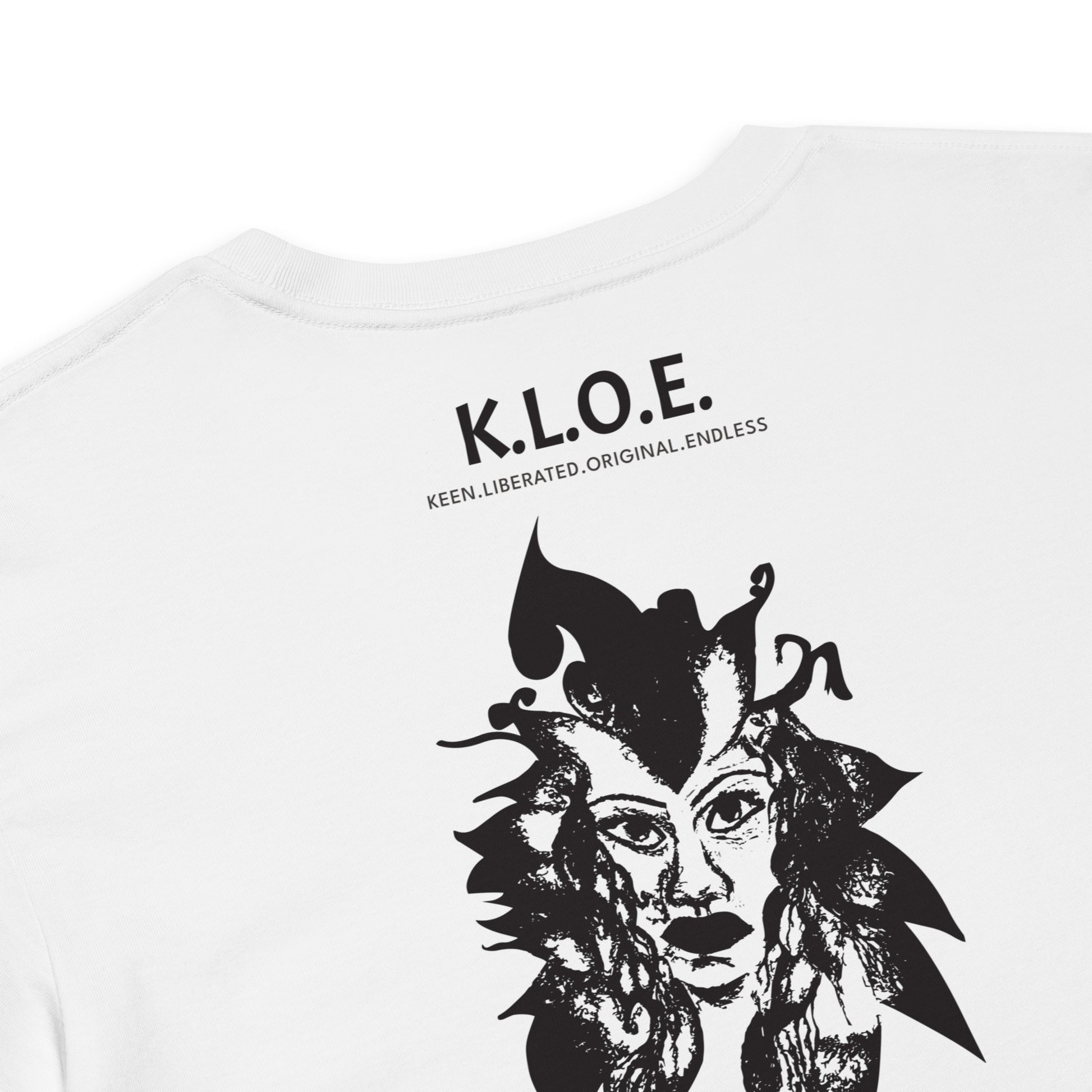 Detail view of a back view of a white K.L.O.E. crop t-shirt showcasing a culturally inspired, hand-drawn black design featuring a bold, expressive face intertwined with flowing, abstract patterns, and K.L.O.E. logo, embodying artistic self-expression and modern bohemian style fashion.