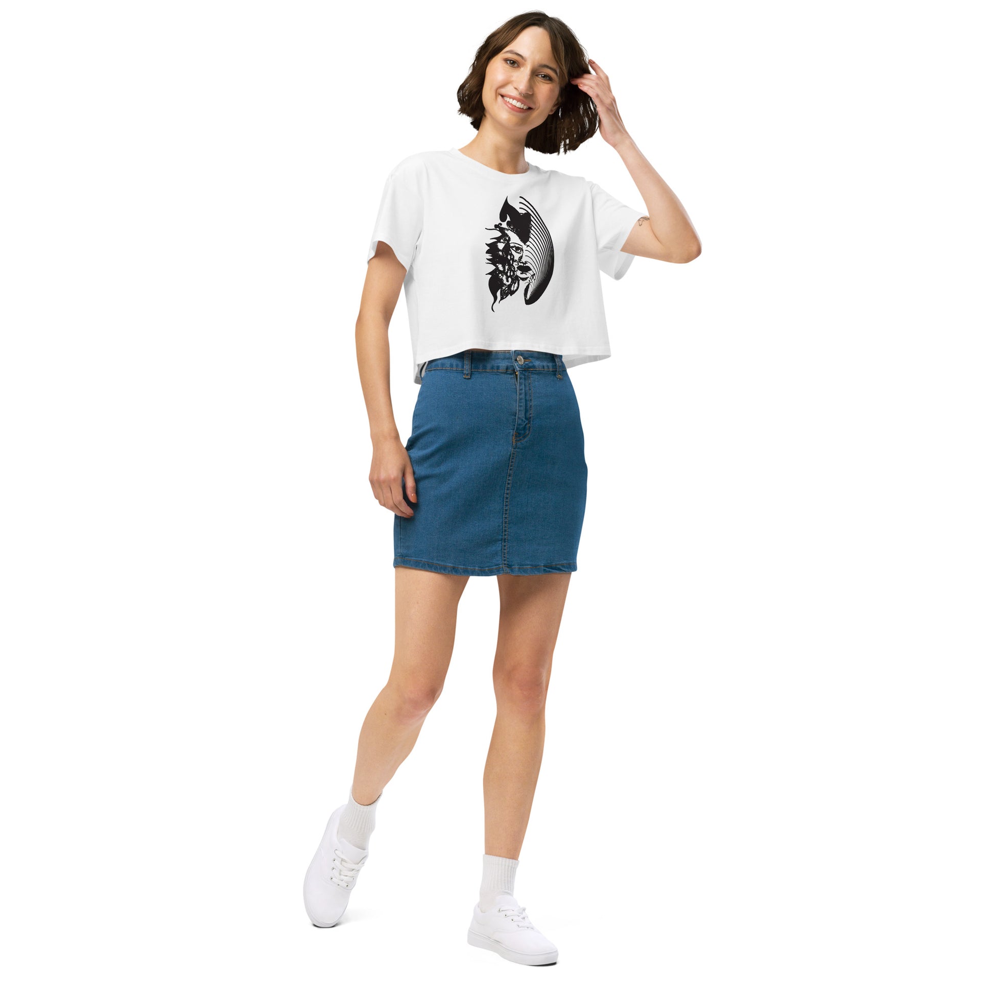 A model wearing white K.L.O.E. crop t-shirt featuring a culturally inspired, hand-drawn black graphic of a bold, expressive face surrounded by intricate details, celebrating individuality and artistic self-expression in modern bohemian style fashion.